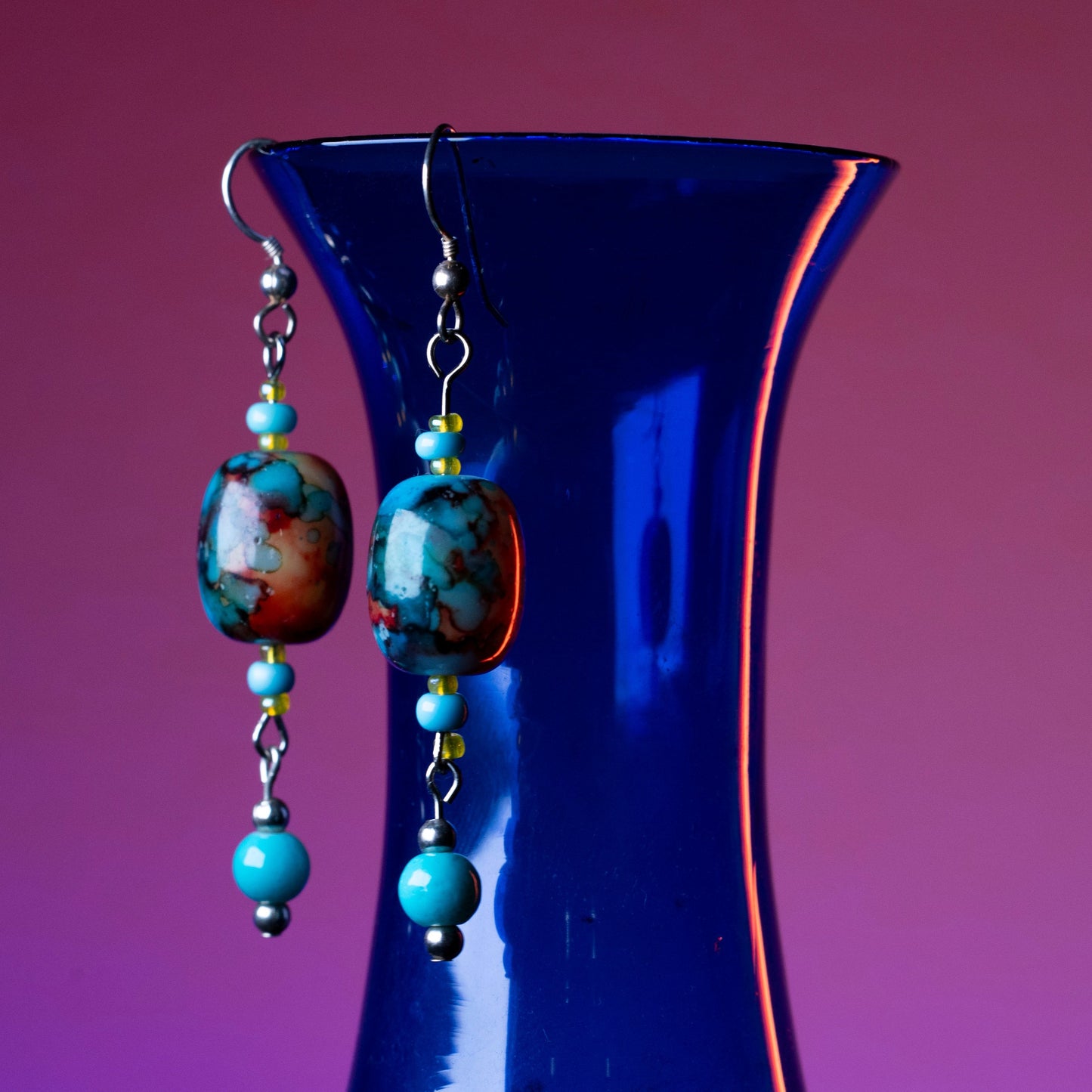 Aurora drop earrings hanging on a blue base.