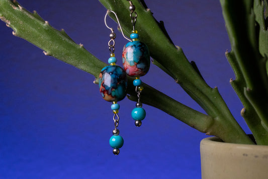 Aurora drop earrings hanging on a blue base