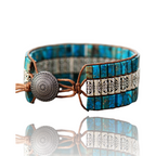 A handmade triple-layer natural stone bracelet with a mix of blue and brown colors, featuring an adjustable strap and a decorative metal button closure.